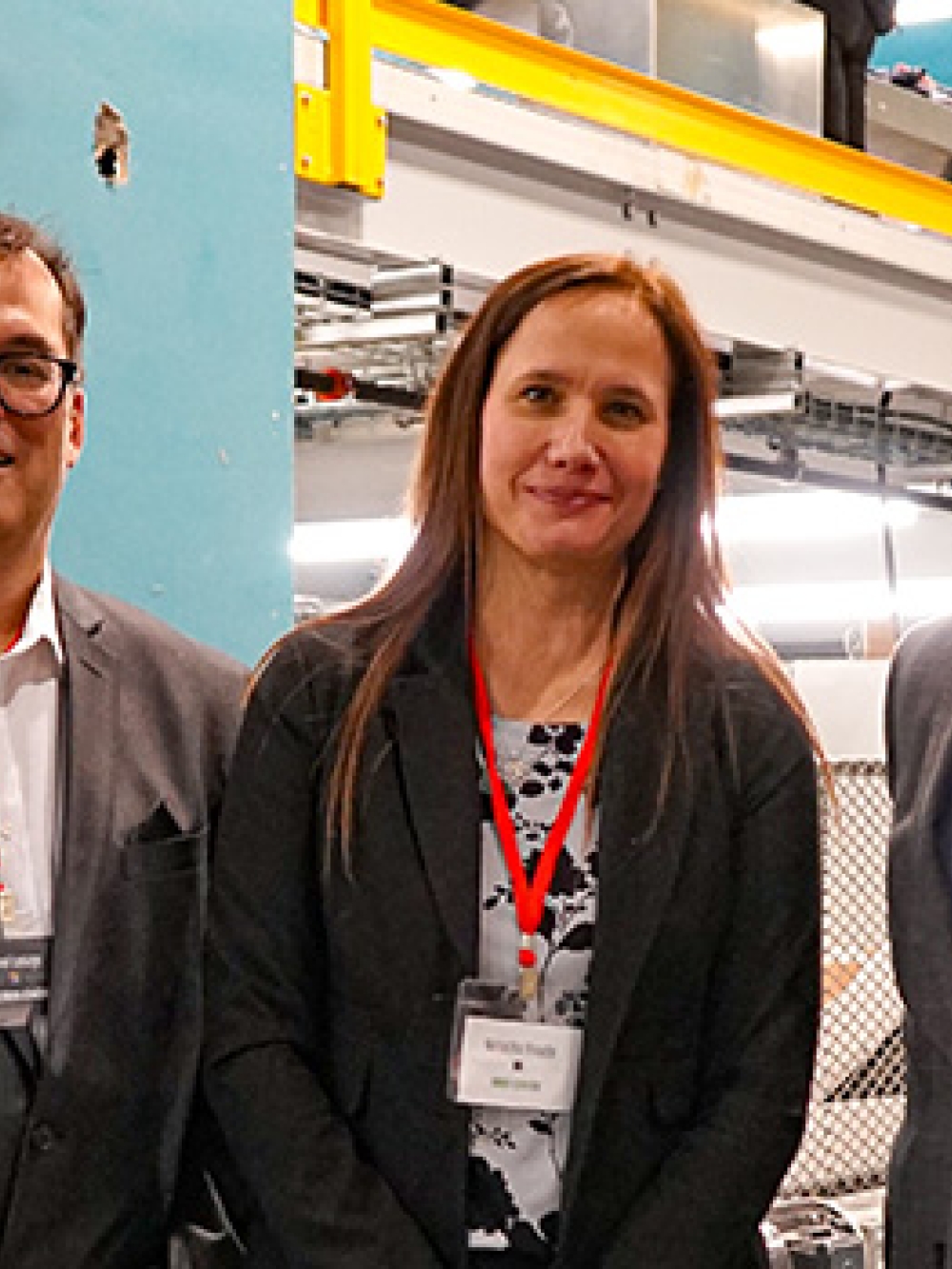 Trois personnes en tenue professionnelle posant devant la nouvelle ligne de tri d’Estrie Aide, avec les équipements industriels visibles en arrière‑plan.