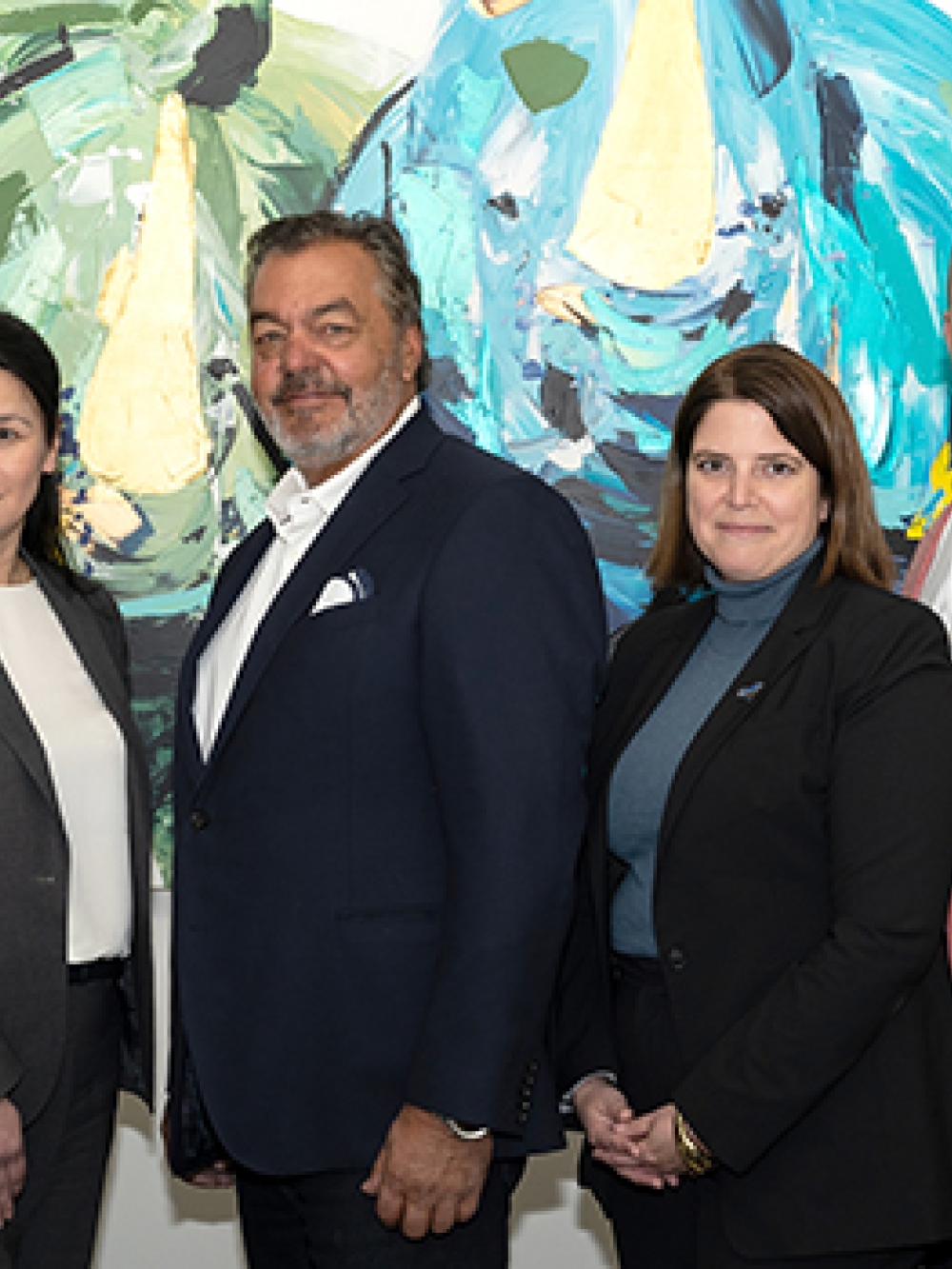 Groupe de personnes en tenue professionnelle posant devant une grande œuvre abstraite colorée dans une salle intérieure.