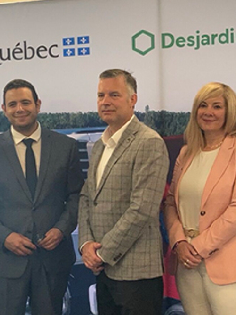 Groupe de personnes posant devant une bannière avec les logos de Manac, Québec, Desjardins et BDC lors d’une annonce officielle.