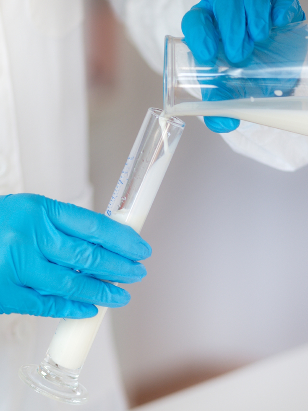 Employé de laboratoire tenant des éprouvettes de lait
