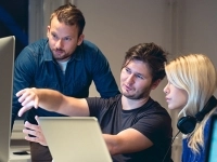 Groupe de personnes travaillant ensemble devant des écrans d’ordinateur dans un environnement de bureau. 