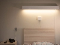 Dispositif mural de surveillance installé au‑dessus d’un lit dans une chambre de soins.
