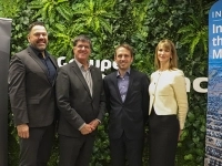 Quatre personnes debout devant un mur végétal, encadrées par deux bannières promotionnelles.