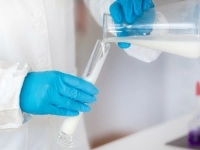 Employé de laboratoire tenant des éprouvettes de lait